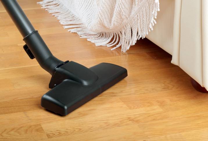 vacuuming wooden floor to remove dust