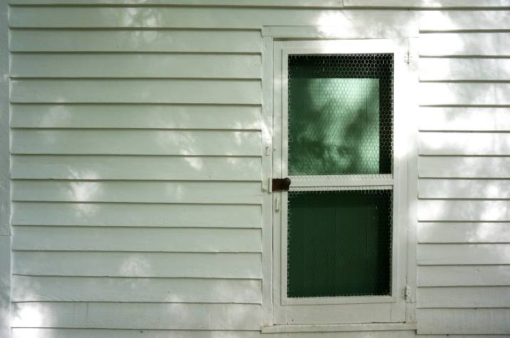 traditional white screen door on a white wall