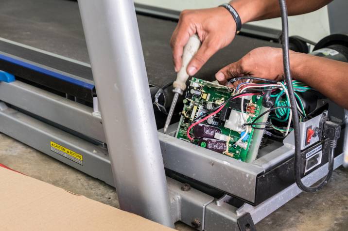 person checking out a treadmill's power cables and lines