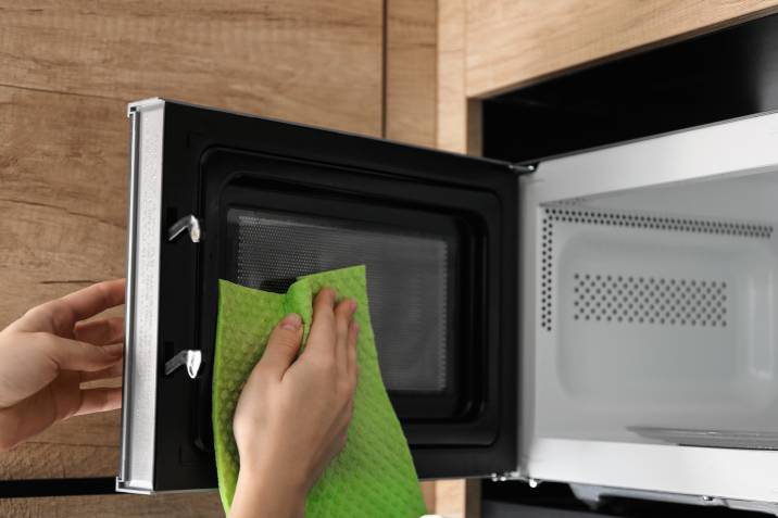 wiping microwave oven door with microfiber rag