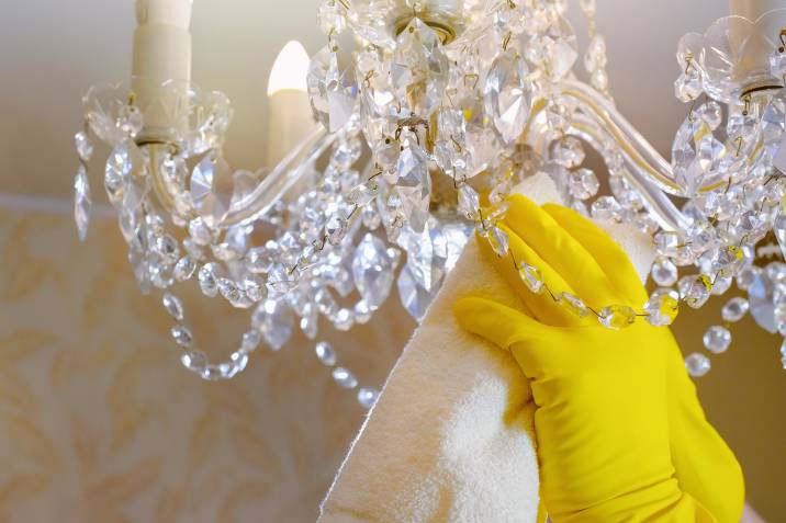hand in gloves cleaning chandelier crystals with a rag