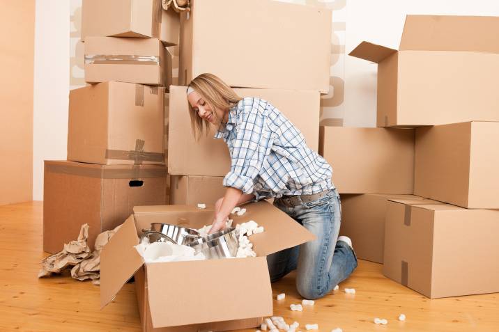 woman packing kitchen pots in moving box