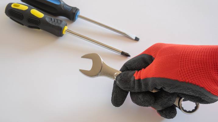 holding a wrench, screwdrivers on the table, tools for disassembling an elliptical machine