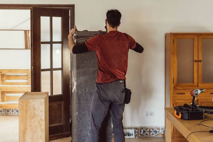 man packing furniture with moving blanket