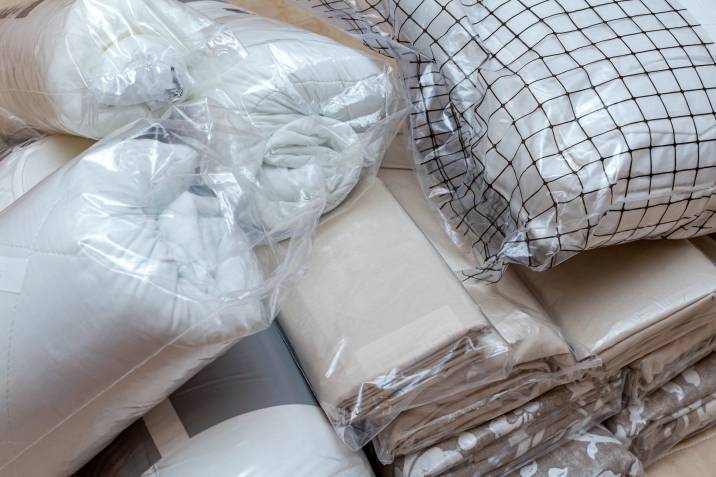 stacks of white, beige linen bedding packed in plastic