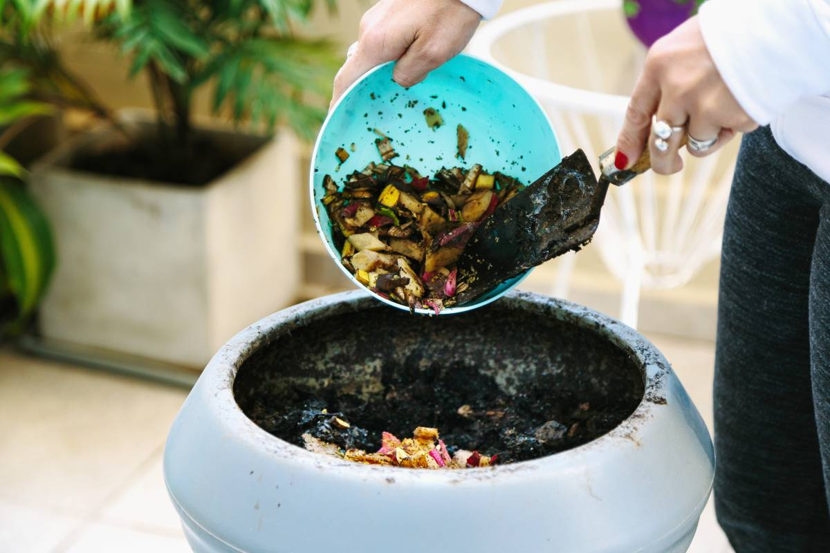 woman throwing vegetable waste into compost bin