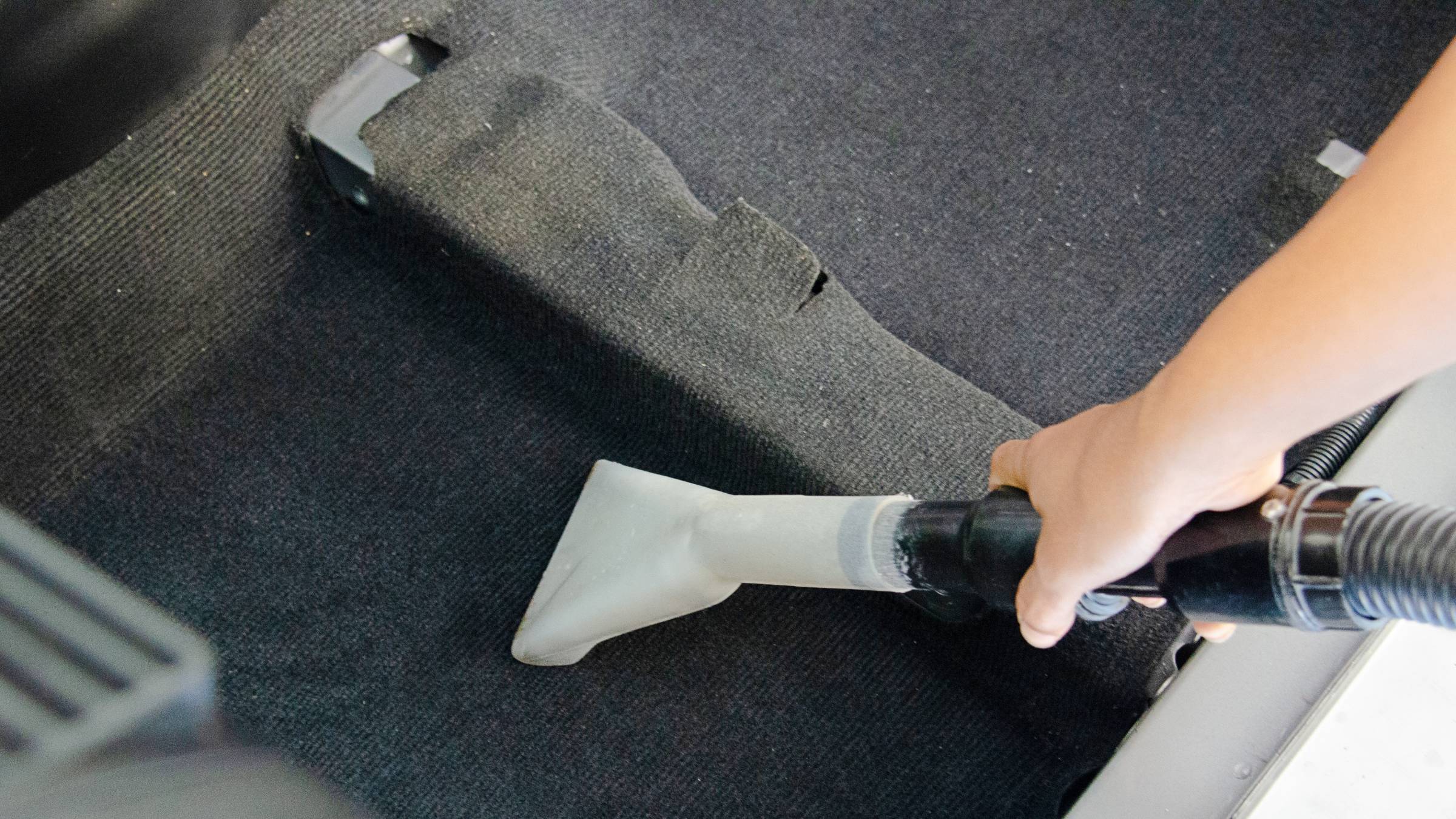 a person vacuuming a car carpet