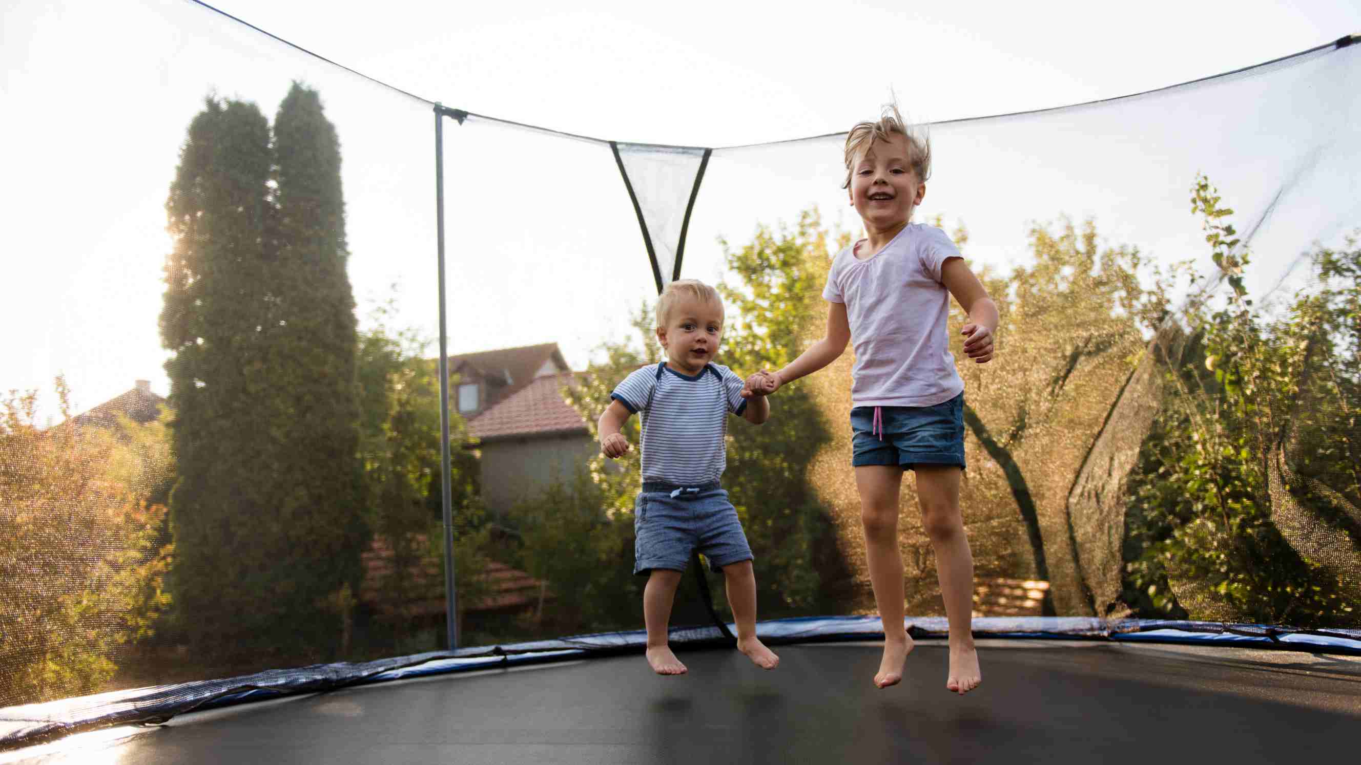 rectangle vs. round trampoline: siblings having fun as they jump on trampoline