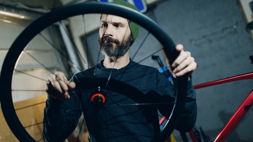 tubeless vs tube: mechanic man checking a bicycle's tire