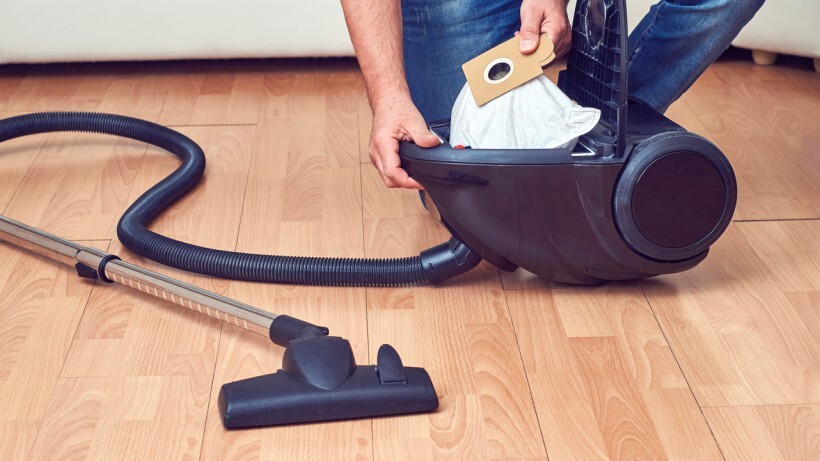 Bagged vs bagless vacuum - A person taking out a full dust bag from a bagged vacuum cleaner