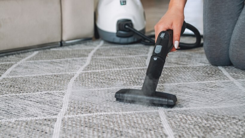 Steam cleaner vs carpet cleaner - a person cleaning the carpet with a steam cleaner