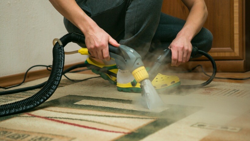 Steam cleaning carpets vs shampooing - a person cleaning a carpet using steam