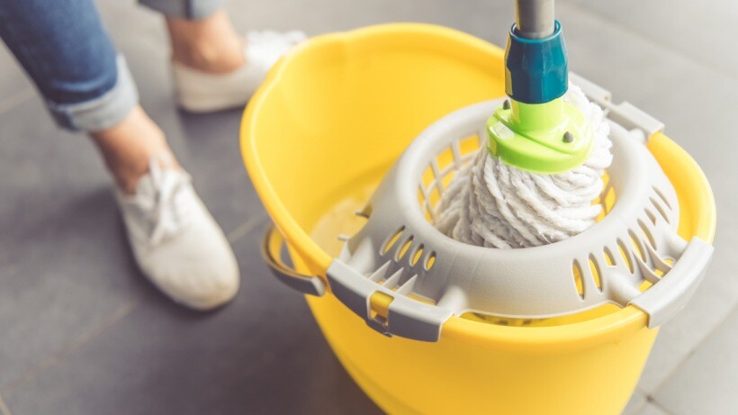 Steam mop, spin mop, or regular mop - a person squeezing mop in bucket for floor cleaning