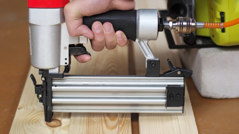 Brad nailer vs finish nailer - A handyperson fixing a clapboard using a nailer