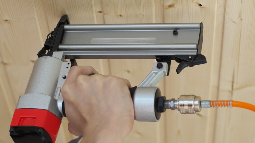 Brad nailer vs finish nailer - A handyperson hammering nails into woodwork with a powerful nail gun