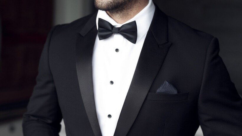 Tuxedo vs suit - A close up of a person wearing a black tuxedo with bow tie