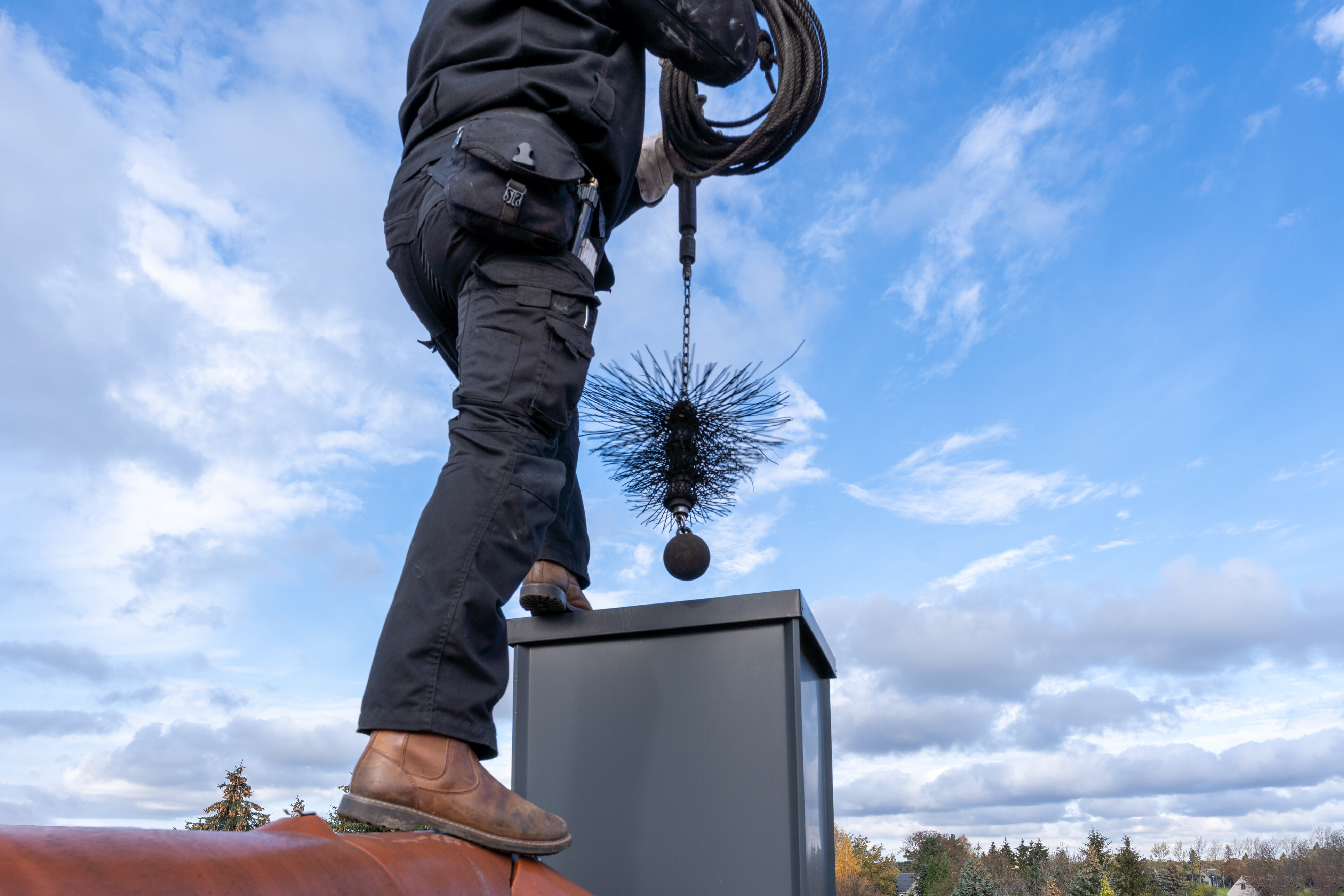 A chimney cleaner is about to put a chimney cleaning tool into a chimney.