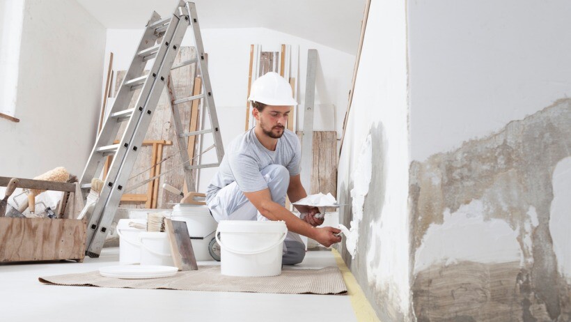 Plastering vs skimming - A plasterer takes plaster from bucket and puts it on trowel to plaster the wall