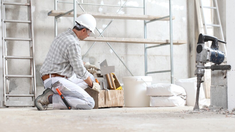 Plastering vs skimming - A skilled plasterer wearing protective gear, works on the interior walls of a building under construction