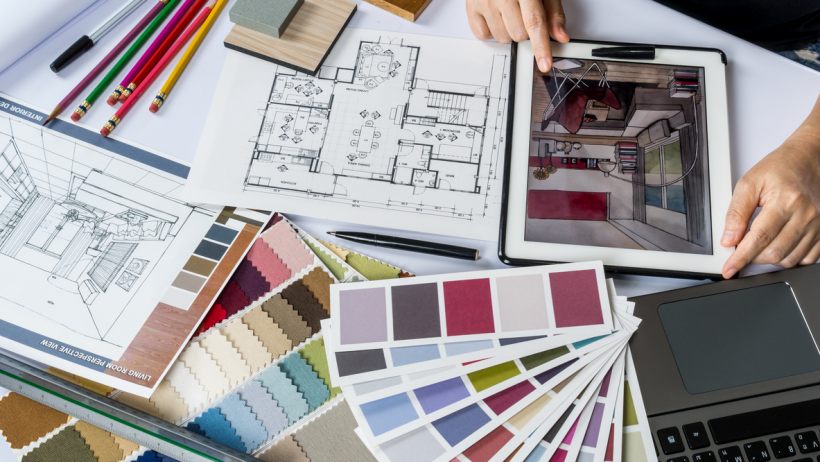 Interior design vs interior decorating - Close-up of an interior designer's hands using a tablet with material samples on desk