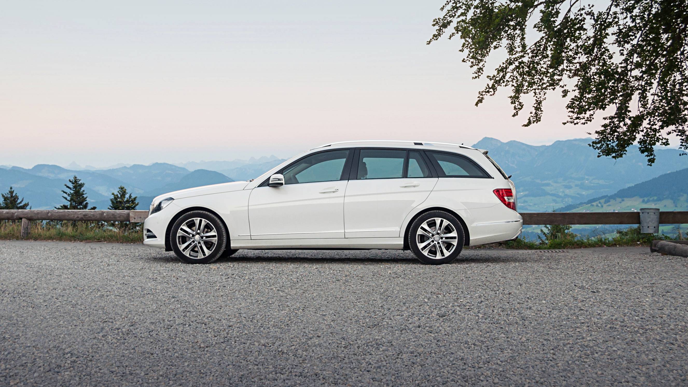 a white Mercedes-Benz station wagon on top of an alpine mountain