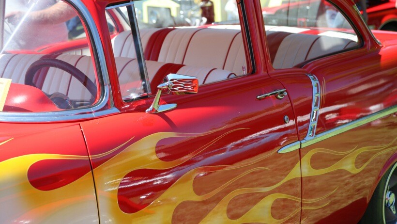 Car wrap vs paint - Close-up view of a vibrant red and yellow classic car with flame decals