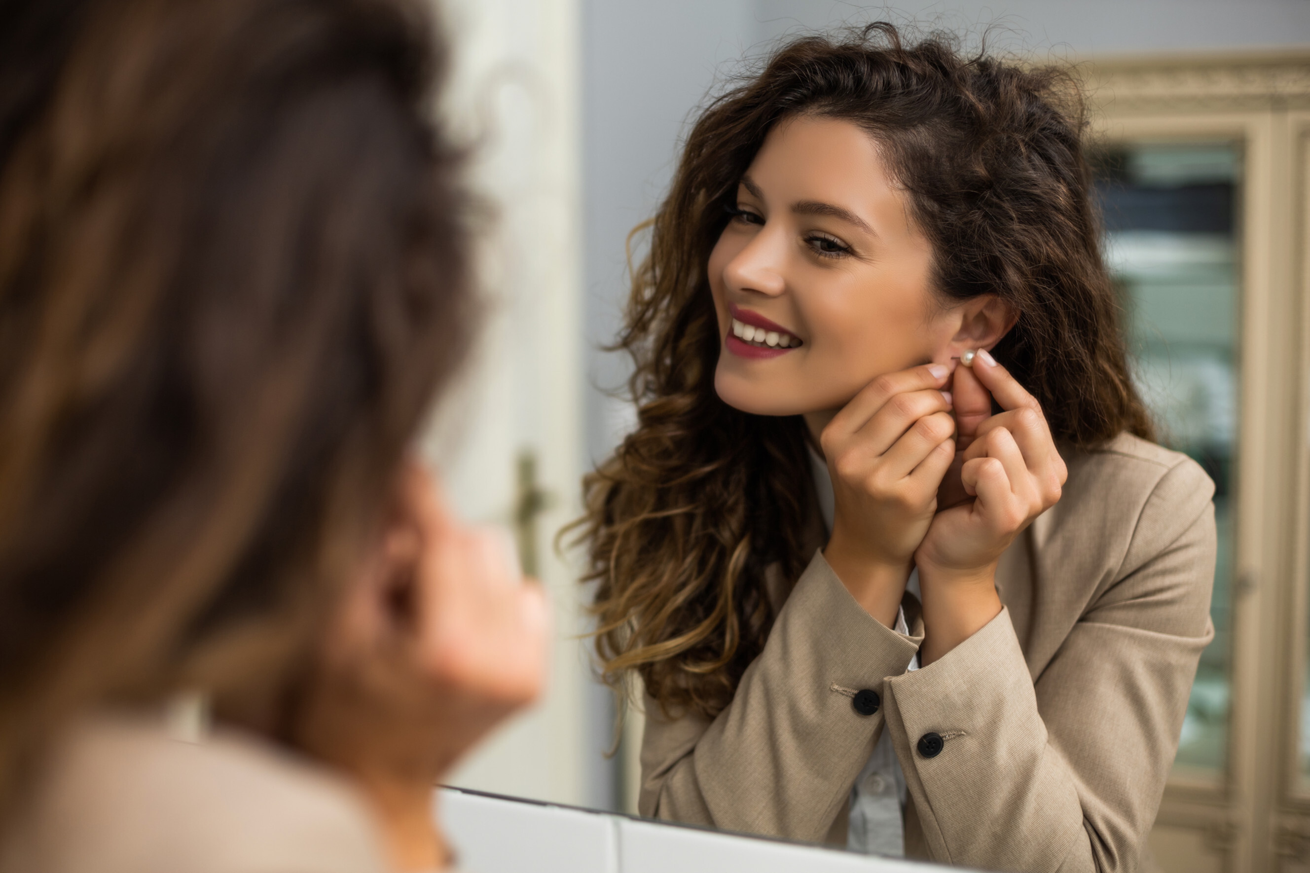 ear piercing cost - woman admiring her new earrings in mirror