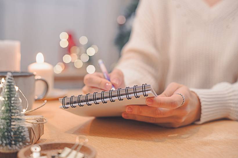 getting ready for the holidays - a woman writing a holiday season checklist