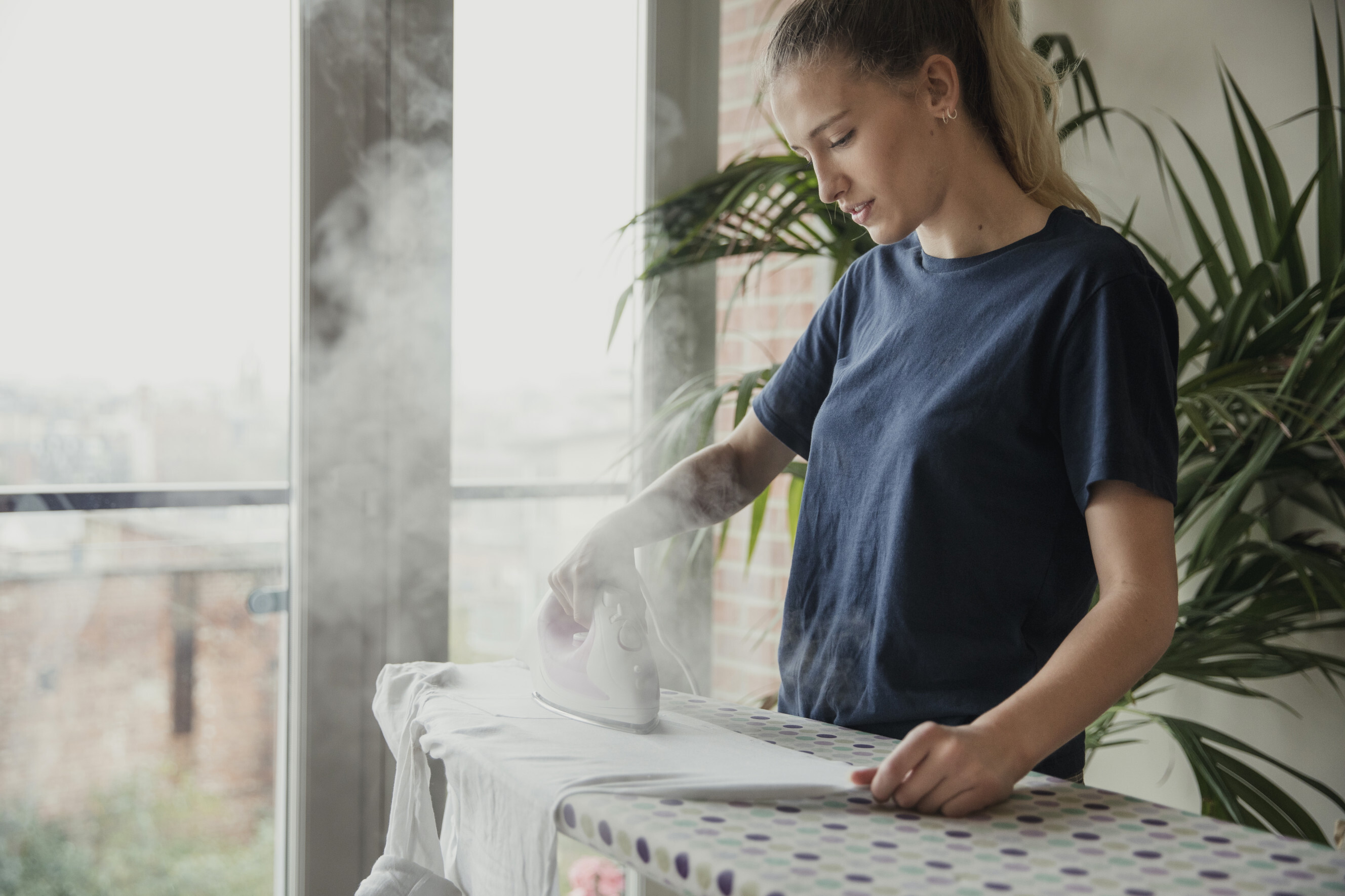 Expert ironing specialist steaming clothes on an ironing board, showcasing professional ironing services near you.