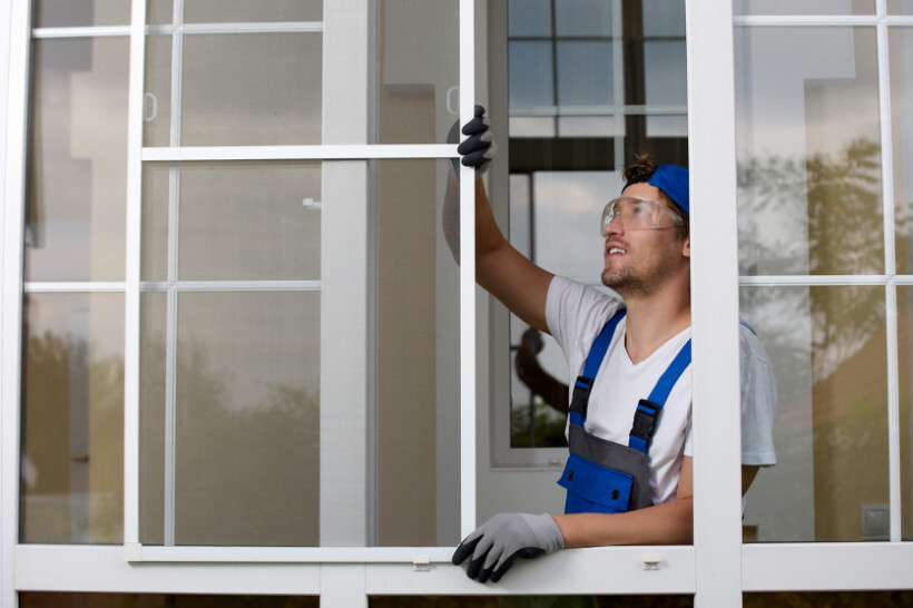 window screen installation - Professional worker installing a window screen outdoors.