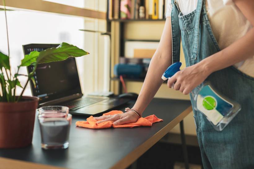 How to stop dust from collecting on desk - a woman cleaning a working desk