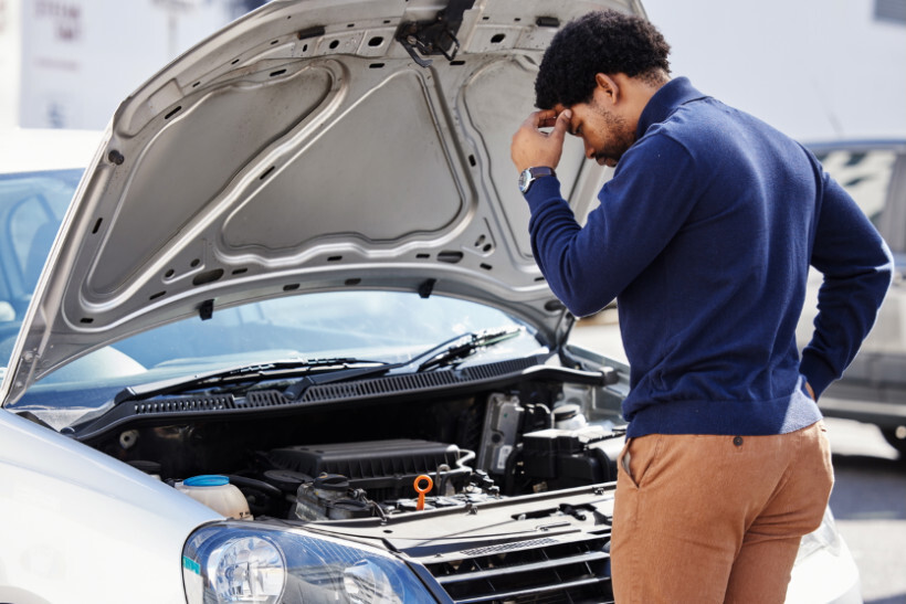 Car diagnostic test - man inspecting a vehicle with an open hood