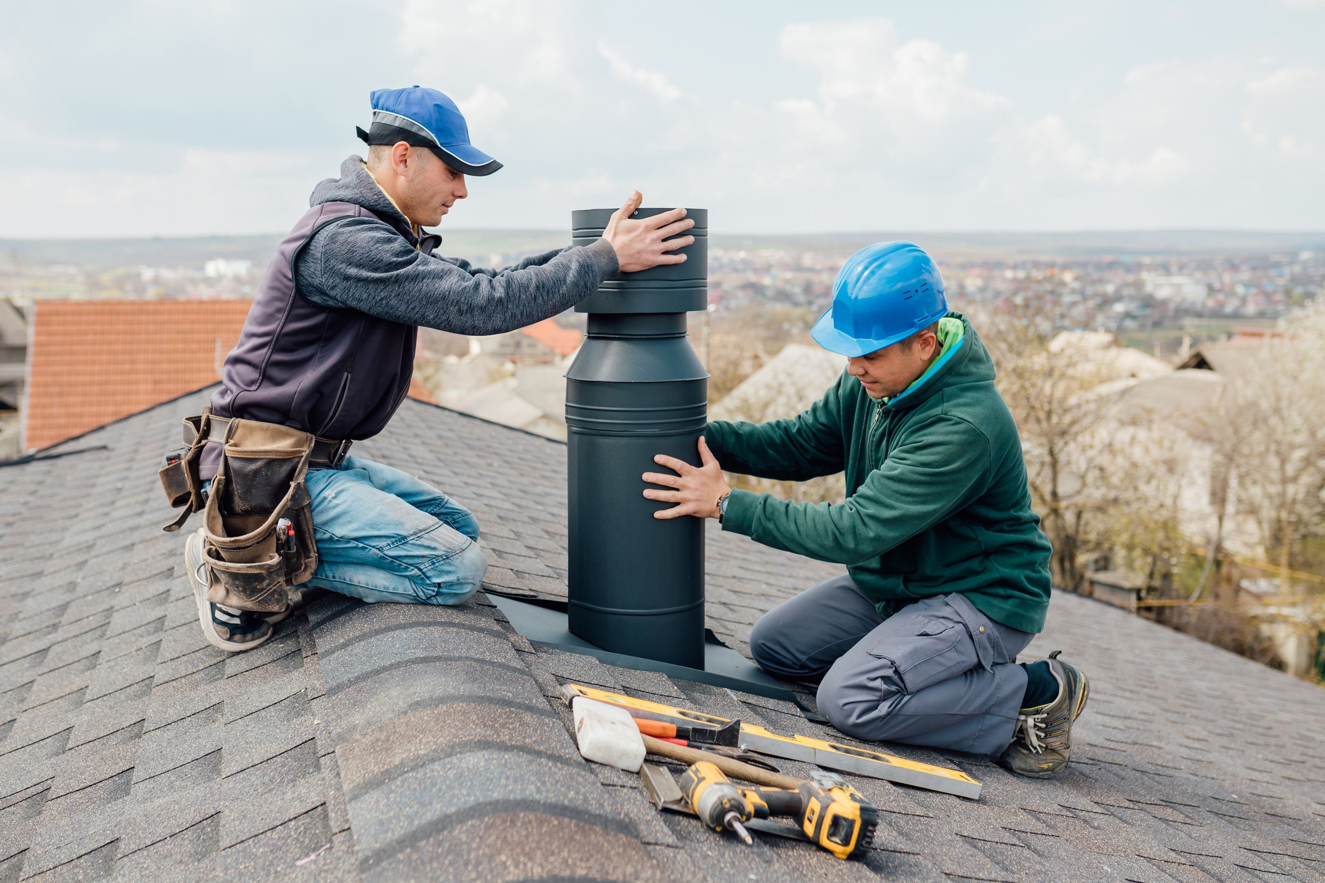 Two professional workmen standing on the rooftop and measuring the chimney symbolizing chimney repair services near me.