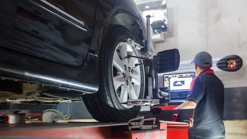 Wheel alignment costs - technician monitoring alignment results on screen