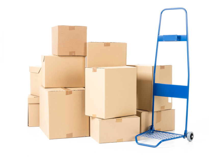 Cardboard boxes next to a blue hand truck on a white background. - hand truck vs dolly