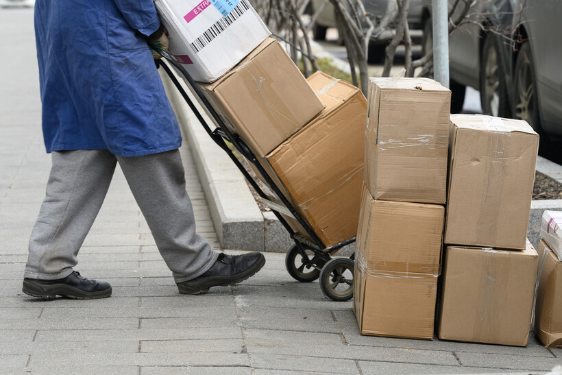 Person moving cardboard boxes with a hand truck on an urban street. - hand truck vs dolly