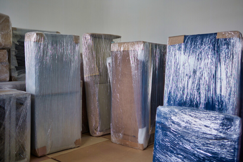 Furniture wrapped in protective plastic film and cardboard for moving. - dolly vs hand truck