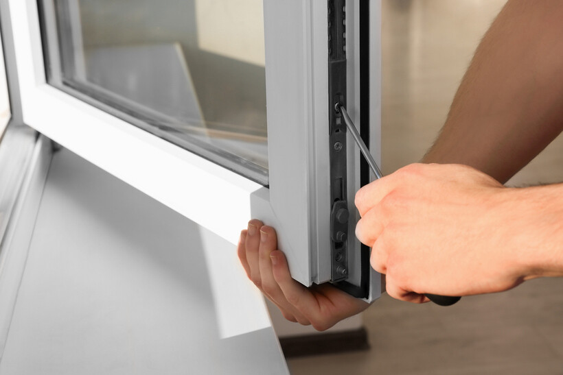 Person adjusting a white uPVC window frame with a screwdriver. - upvc vs aluminum windows
