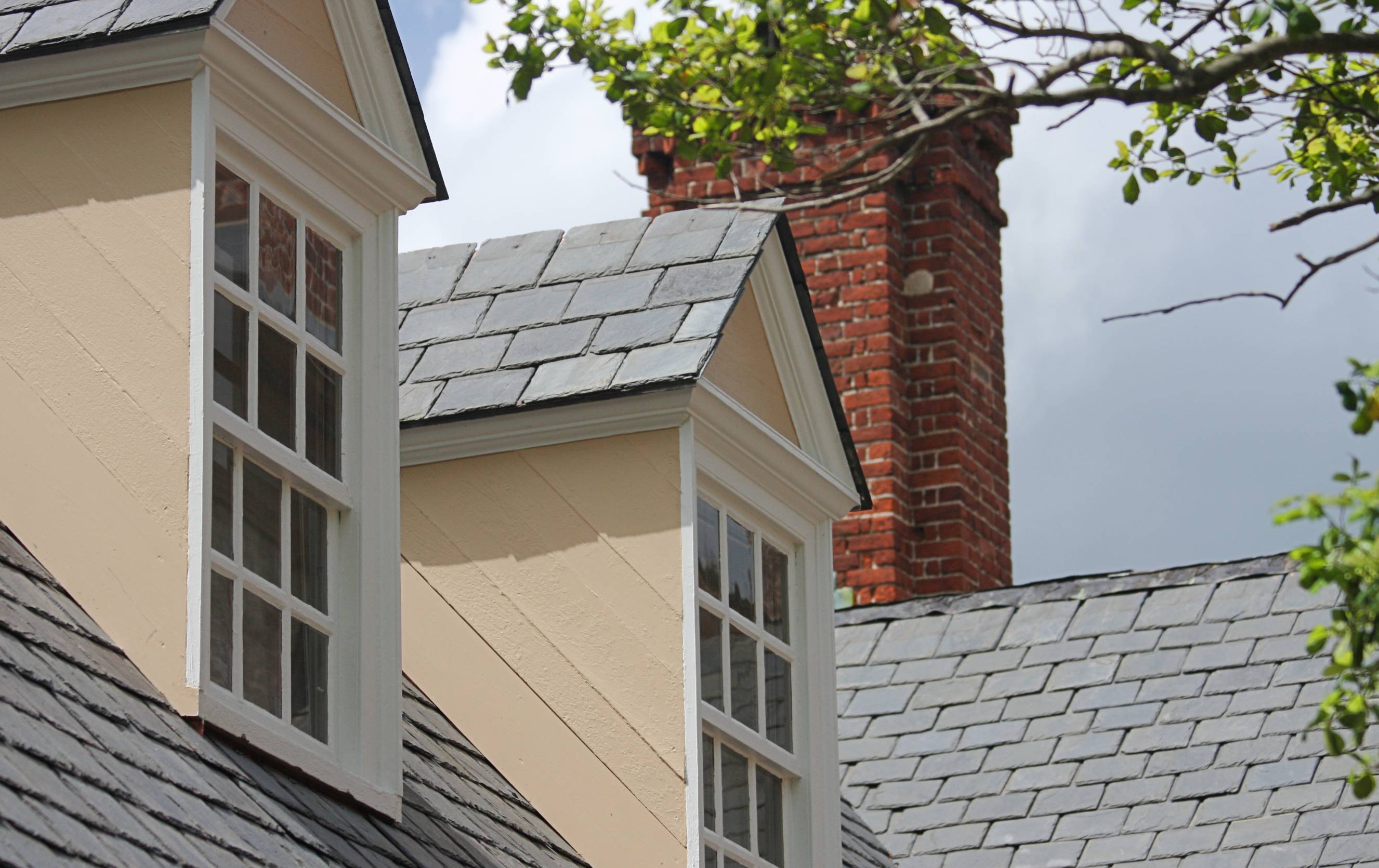 Traditional house roof with slate shingles and white-framed dormer windows