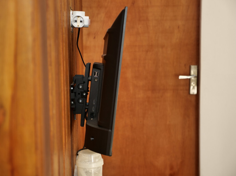 how to wall mount tv – Side view of a flat-screen TV mounted securely to wooden wall studs.