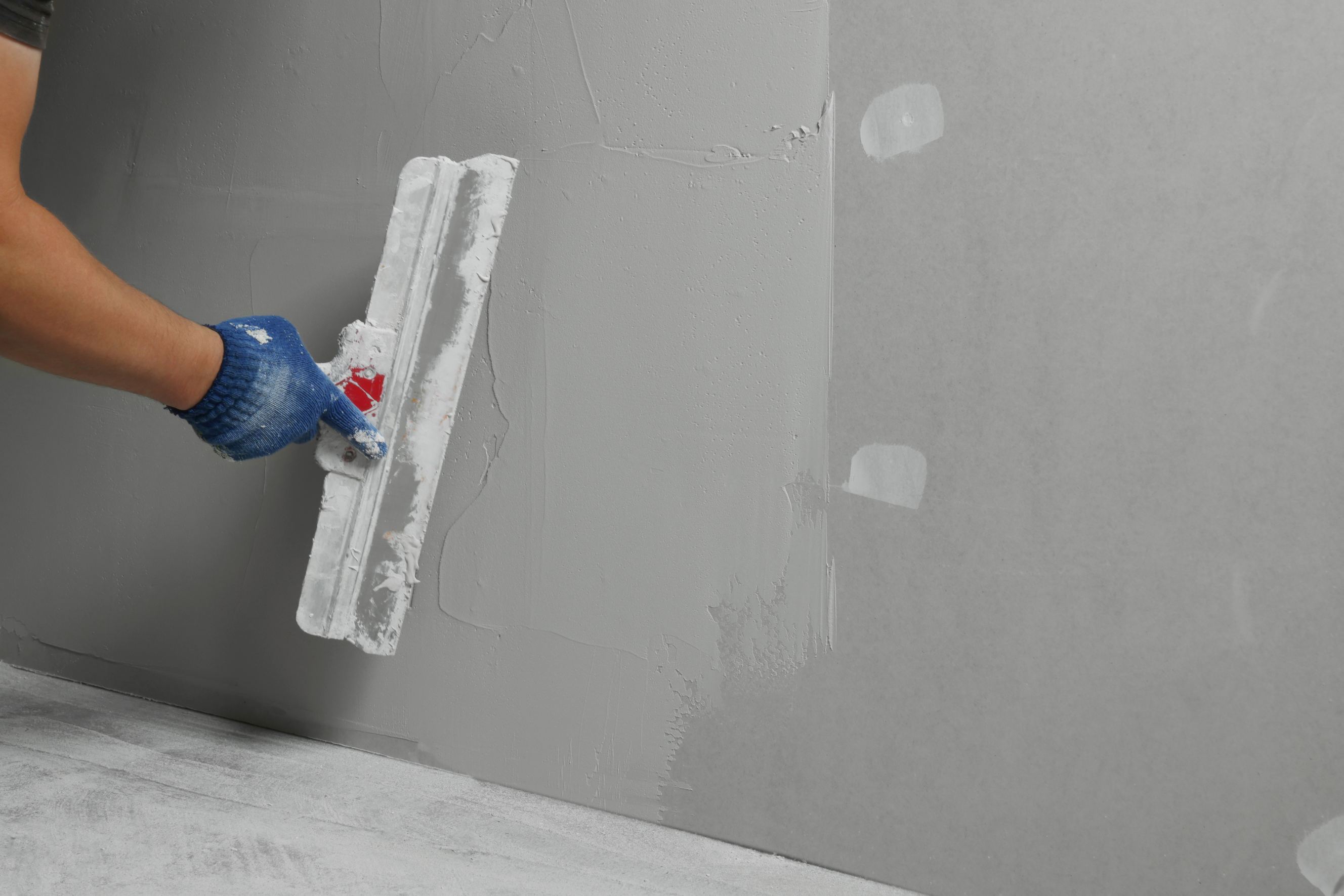 Professional worker plastering wall with putty knife, closeup representing stucco repair near me.