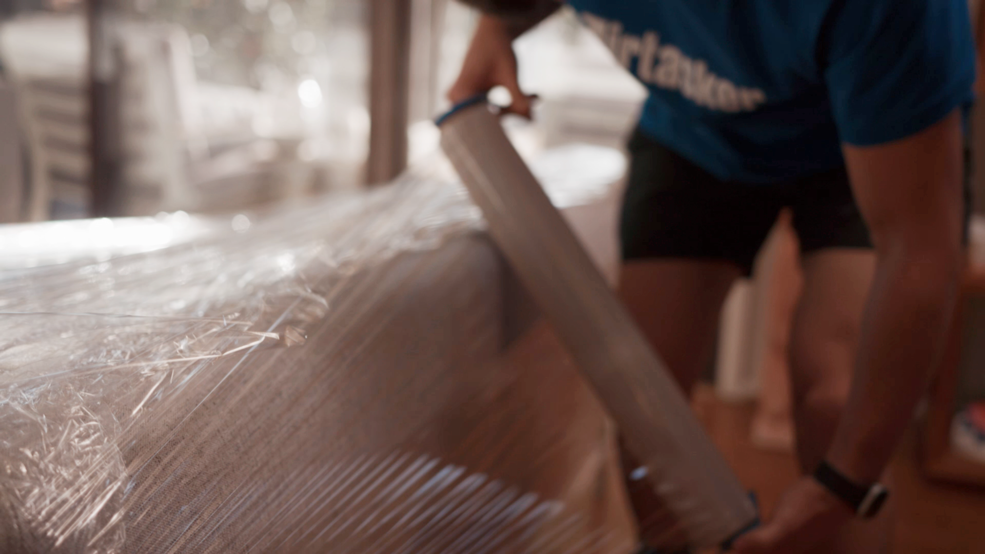 cost to move furniture - Person wrapping a sofa with plastic film for protection