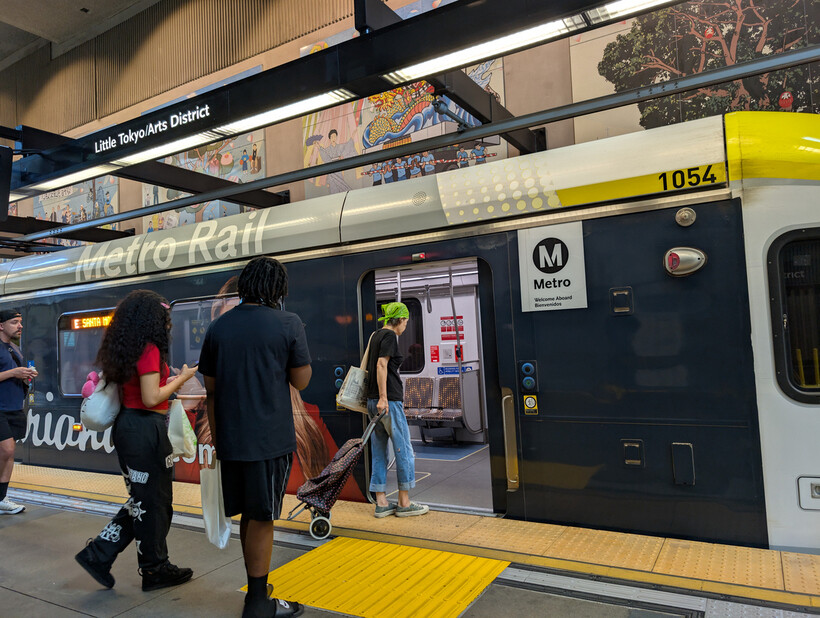 Commuters waiting on the platform as a light rail train approaches. - moving to Los Angeles