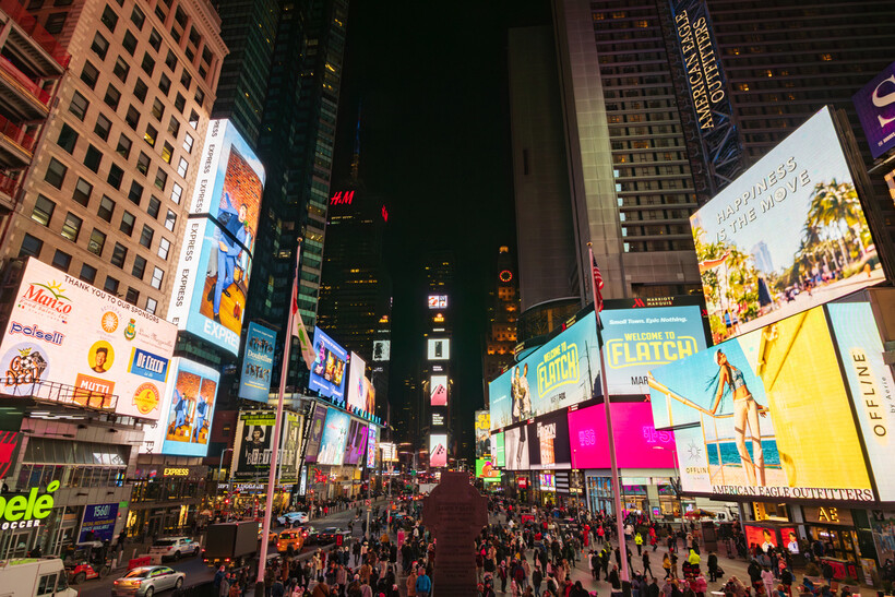 Crowds of people walking through the lit streets of Times Square in the evening. - moving to NYC