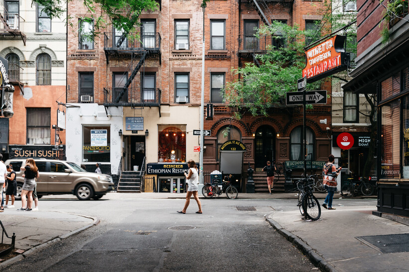 Cars parked along a tree-lined residential street in Greenwich Village on a sunny day. - how to move to New York