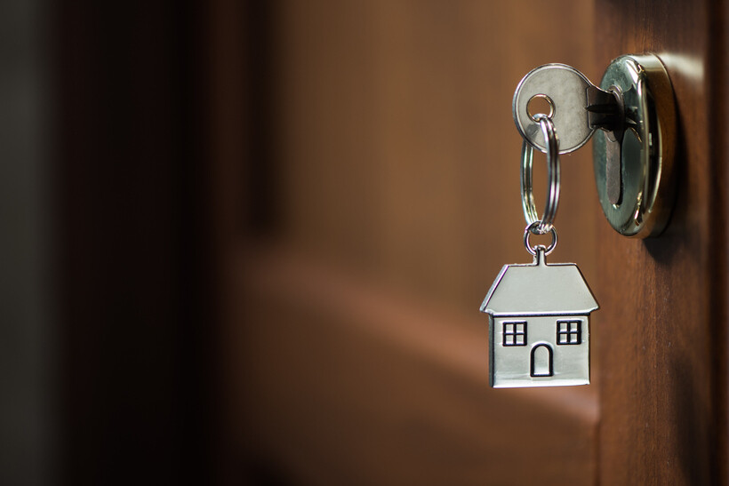 A close-up of a silver house key being inserted into a door lock. - moving to NYC