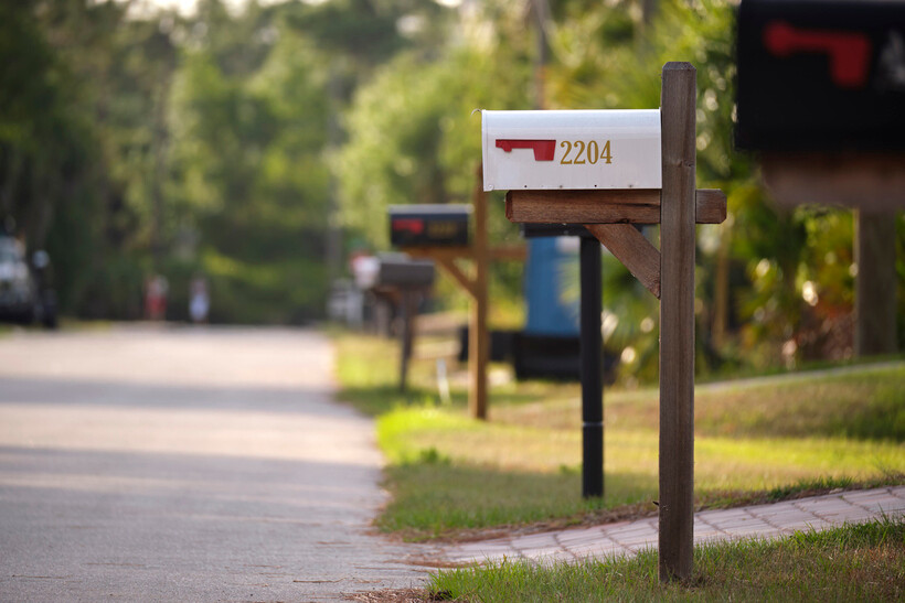 Post-mounted residential mailbox located along a paved suburban road. - how to replace a mailbox