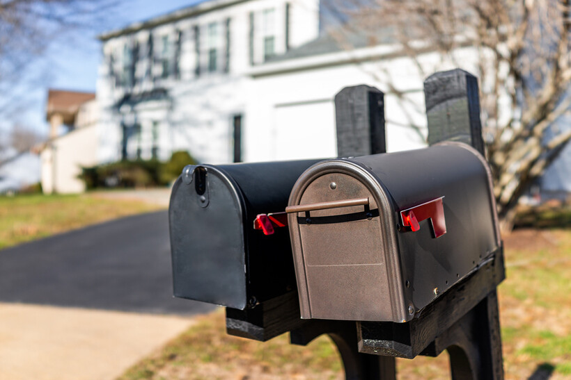 Close-up of residential mailboxes with red flags mounted on a wooden frame. - how to replace a mailbox