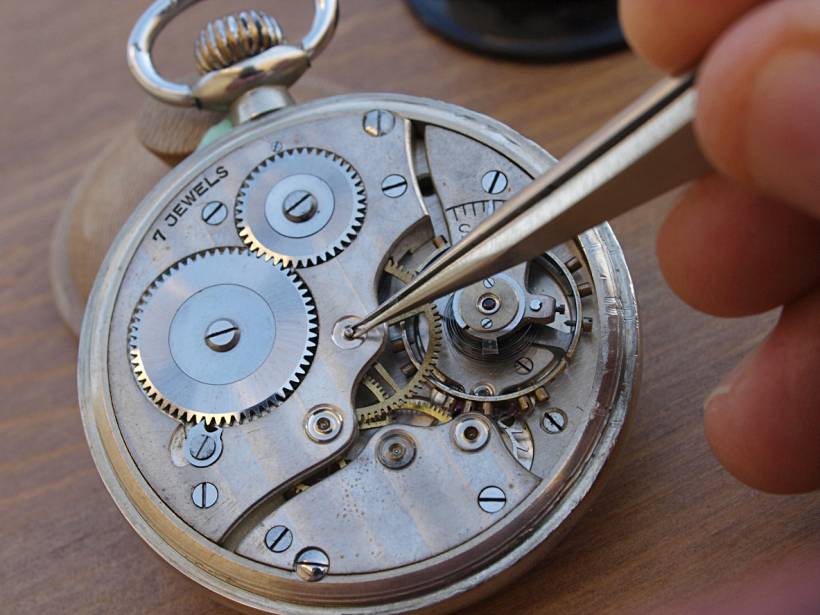 how much does clock repair cost - Close-up of a clock mechanism being repaired with precision tweezers