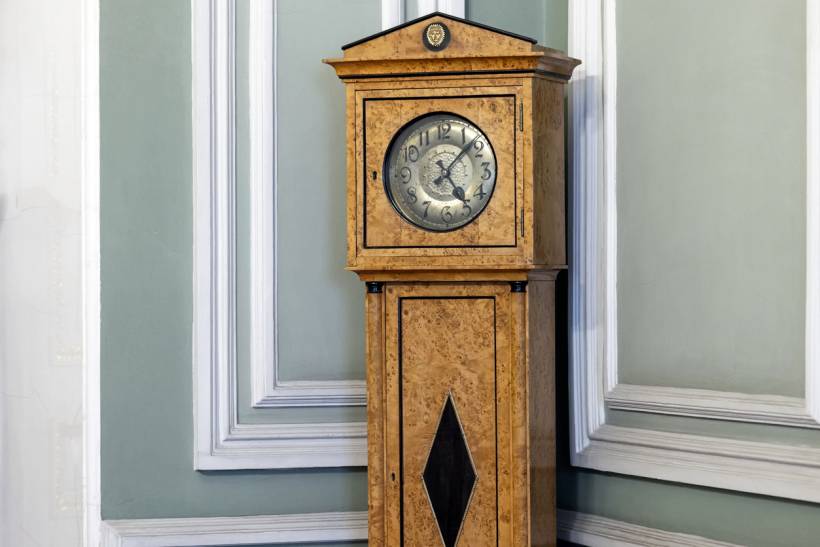 how much does clock repair cost - Antique grandfather clock with a wooden case standing in a classic interior